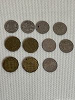 Twelve United Kingdom coins arranged on a textured fabric background, showcasing both sides of the coins including silver-toned and brass-toned varieties.
