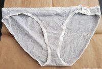 Front view of gray bikini style plus size underwear with white lace trim and tagged 'Jeuni'.