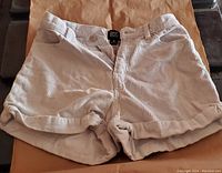 Front view of the white corduroy shorts showing the pockets, button closure, and cuffed hems.