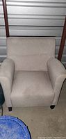 Front view of beige fabric armchair in lightly used condition.