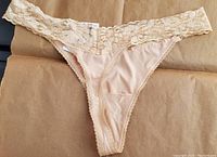 Front view of I.N.C. thong underwear showing almond latte color with floral lace waistband and smooth fabric front panel.