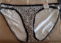 Front view of cheetah print bikini bottom with black trim and tags attached.