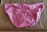 Hot pink bikini bottom laid flat, showing back side with smooth fabric and simple design.