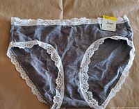 Gray women's underwear with white lace trim on waistband and legs, brand tag attached showing Jenni brand and size M/Medium, new condition