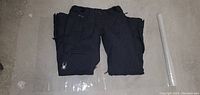 Folded pair of black Spyder snow pants showing front pocket and logo detail on leg.