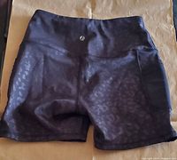 Black women's yoga shorts folded showing front side with subtle animal print pattern and high waistband