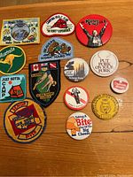 All patches and pins laid out on wooden surface showing full set including camping and promotional themes