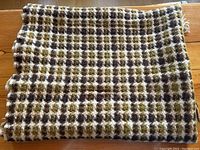 Folded Pendleton wool blanket showing earth-tone checkered pattern