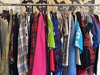 Rack of assorted vintage clothing including dresses, shirts, sweaters, and robes