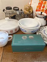 Image showing various vintage kitchenware items including CorningWare covered casserole, Fire King bowls, and a green box with salt and pepper shakers.