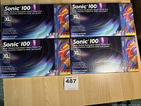 Four boxes of Sonic 100 nitrile medical examination gloves, powder-free, XL size on floor.