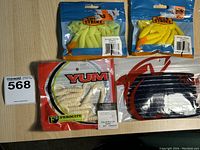 Lot of four packs of new fishing baits including two Strike King brand packs in yellow and light chartreuse, one YUM brand white Ferocity grubs, and one black colored pack.