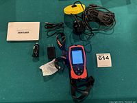 Full set of the LuckyLaker portable fish finder and accessories laid out on a surface, showing the fish finder device, transducer with cable and float, car charger, power adapter, lanyard, and user manual.