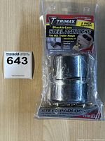 Photo of open package containing two Trimax shacke-less steel padlocks and six brass keys on a wood surface with MaxSold tag.