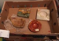 Four ashtrays placed inside a box, varied stone colors and shapes visible.