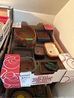 Seven bonsai pots of various shapes and sizes arranged in a cardboard box.
