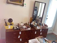 Full frontal view of teak dresser with matching mirror leaning against wall, assorted items on top