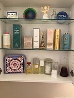 Three shelves with assorted perfume bottles, skincare creams and decorative items.