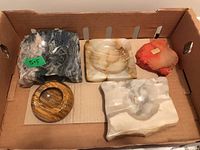 Overview of five vintage stone ashtrays in cardboard box, showing variety of shapes and colors