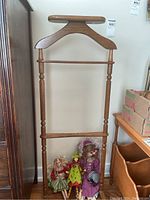 Full view of the wooden valet stand with some dolls placed at the base for scale.