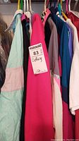 Multiple colorful vintage jackets and shirts hanging on rack including pink and turquoise items