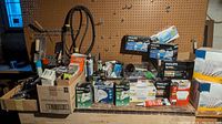 Wide view of workbench top and shelf with boxes and grouped items including Philips bulbs and hardware parts