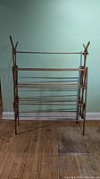 Front view of the wooden expandable clothes drying rack showing multiple horizontal rods and A-frame supports.