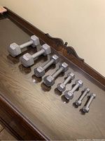 Set of all dumbbells lined up on a polished wooden surface showing all pairs in ascending weight order.