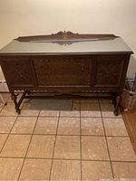 Front view of oak sideboard with closed doors and glass protective panel on top.
