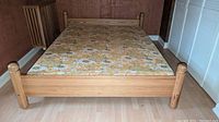 Front view of bed with floral-print mattress laid on slatted frame