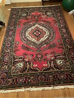 Full top view of rectangular red-field rug on hardwood floor