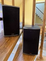 Pair of speakers with black magnetic grills installed on composite cabinet