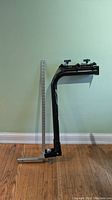 Full view of the Swagman bike rack mounted vertically against a light green wall with a measuring stick beside it for scale.