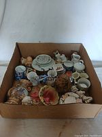 Box with assorted ceramic knick knacks shown from above, displaying varied sizes and shapes of items.