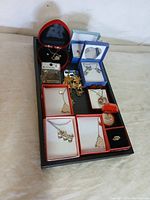 Wide view of jewelry items on black tray showing multiple jewelry pieces in original cases.