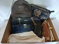 Full view of all handbags and accessories in the lot arranged in a box, featuring a variety of Michael Kors branded handbags and wallets.