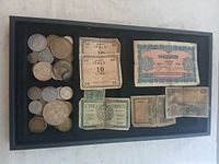 Overview photo of collection in black display tray showing various coins and banknotes including Italian Lire and French Francs.