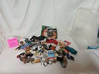 Wide angle of entire lot showing assorted collectible items spread out on white sheet including toys, lighters, coins, jewelry and electronics