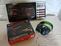 Overview photo showing the boxed iBUYPOWER Aresie 1 keyboard, boxed Creative Sound BlasterX AE-5 PCIe DAC sound card, and the black and green wired headset.