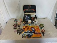 Overview photo of all Lootcrate themed items arranged on beige cloth background. Shows multiple collectible figurines, a Lootcrate branded box, printed materials, and other small items.