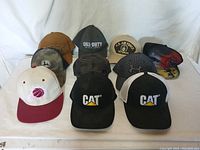 Photo showing 10 assorted baseball style hats including CAT, John Deere, Call of Duty, U.S. Air Force Veteran and others.