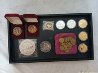 Collection of assorted machine tokens displayed on black tray with some in cases and pouches