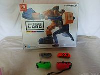 Nintendo LABO Robot Kit in original box with four Nintendo Switch Joy-Con controllers in different colors (clear, neon red, neon green, neon pink) visible outside the box.