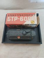 Photo of the toy BTR-60PB armored personnel carrier displayed next to its original box with Russian text.