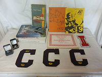 Full view of the collection showcasing yearbooks, junior varsity letter, varsity letter patches, class rings in boxes, and a school pennant.