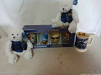 Two white plush bears wearing blue plaid scarves, boxed set of four glassware and a Polar Express themed mug