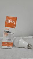 Photo showing a white Tento LED light bulb and its original packaging box with specifications including 10 watts, 700 lumens, E27 base, and 20000 hours lifespan.