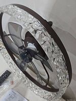Side angle of the crystal ceiling fan showing the faceted glass ring and five transparent blades.