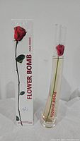 Flowerbomb perfume bottle with red rose inside displayed next to its outer box packaging