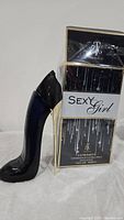 Photo of Sexy Girl perfume tester bottle shaped like a black high-heeled shoe with gold heel next to original packaging box